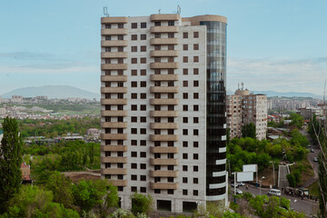 Modern residential building in Erevan surrounded by greenery and mountains during daylight