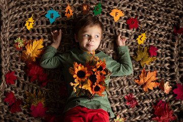 child laying on blanket with fall decor and thankful sign