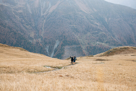 Two hikers pointing on a golden meadow in alpine terrain