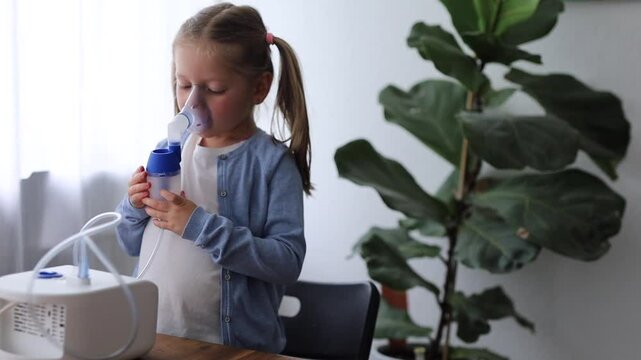 A 5-year-old girl at home uses a nebulizer, taking deep breaths to aid her respiratory health