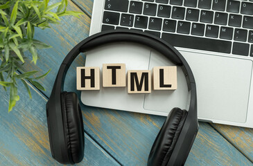 HTML text on cubes lying on a laptop on a wooden background.