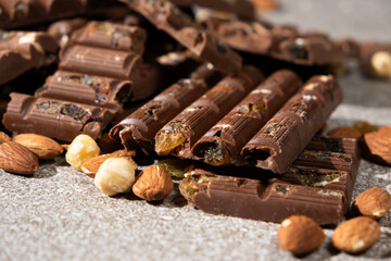 Lots of chocolate bars with nuts and raisins on a gray background