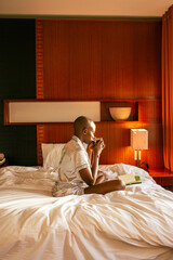 A young black woman with a shaved head waking up on  on a sunny summer morning in a lovely cozy room