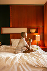 A young black woman with a shaved head waking up on  on a sunny summer morning in a lovely cozy room