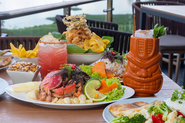 Banquete de ceviche y jalea mixta con bebida en baso tiki