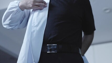 A sushi chef prepares for work by putting on and adjusting his apron, highlighting the importance of professionalism and readiness in the kitchen. Ideal for culinary and sushi-making content.