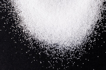 Macro crystals of white rock edible salt on black background space for text