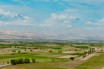 Expansive verdant fields and distant mountains viewed from a high vantage point in Armenia