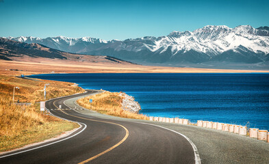 S-shaped winding driveway extending towards snow-capped mountains along the Sayram Lake (Sailimu...