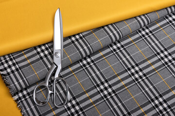 Flat lay photography of plaid  pattern fabric for suits with yellow accent line. On top of it is a...