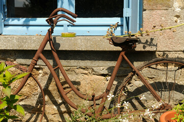 Old rusty bicycle leaning against the window sill of an old French house.