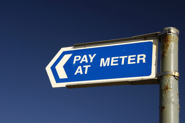 Pay at meer sign in car park against blue sky.