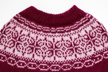 Burgundy purple wool winter christmas sweater with contrast jacquard pattern close-up. Clothes for photo shoot. Handmade clothes. Two-color knitting.