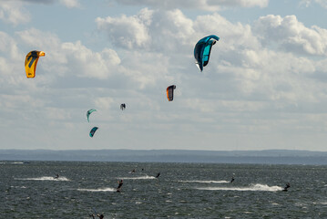 People swim on the sea on a kiteboard or kitesurfing. Kitesurfing lessons on the bay. Summer sport learning how to kitesurf. Kite surfing on bay. Hel Peninsula,Puck bay, Jastarnia, Poland.