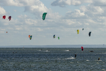 People swim on the sea on a kiteboard or kitesurfing. Kitesurfing lessons on the bay. Summer sport learning how to kitesurf. Kite surfing on bay. Hel Peninsula,Puck bay, Jastarnia, Poland.