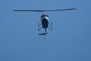 Blue Helicopter fly on sunny day on the clear blue sky.