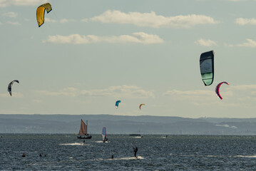 People swim on the sea on a kiteboard or kitesurfing. Kitesurfing lessons on the bay. Summer sport learning how to kitesurf. Kite surfing on bay. Hel Peninsula,Puck bay, Jastarnia, Poland.