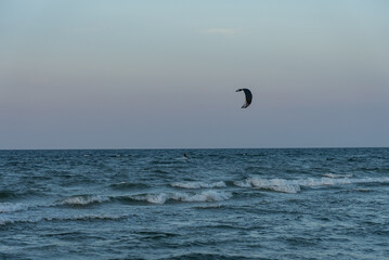 People swim on the sea on a kiteboard or kitesurfing. Kitesurfing lessons on the bay. Summer sport learning how to kitesurf. Kite surfing on bay. Hel Peninsula,Puck bay, Jastarnia, Poland.