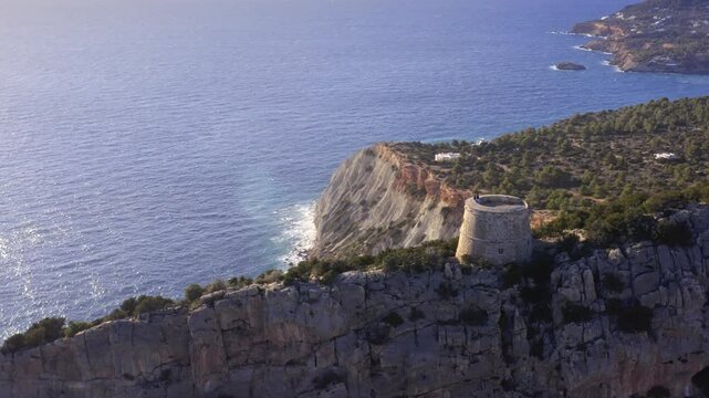 Ibiza&rsquo;s Torre des Savinar and Mediterranean Coastline &ndash; Aerial Flyover Closeup of Historic Tower and Scenic Shores in Deep Blue Waters &ndash; Drone Tracking