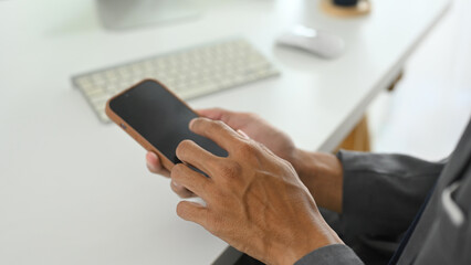 Close up shot of businessman holding mobile phone with white empty display