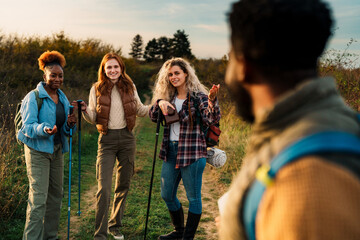 A black man hiker shrugs at his friends, showing he doesn't know where they are they look curious at him.