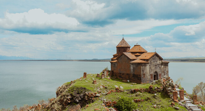 Sevanavank Monastery perched on a cliff by Lake Sevan in Armenia under a cloudy sky