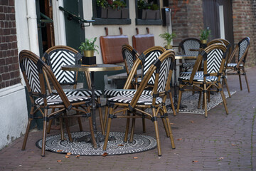 An empty terrace at a cozy outdoor café in the old town, with neatly arranged tables and chairs. The peaceful, rustic setting invites passersby to relax and enjoy the ambiance of the historic area.