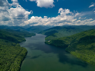The Vidraru hydroelectric dam seen from the drone. Huge mountain lake at the edge off a big and wild forest in the summer season