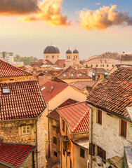 Obraz premium beautiful old city sunset landscape with ren and orange tile roofs of houses and nice cathedral church in traditional venetian style with bell tower and chapel and evening sky on background
