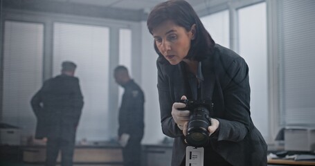 Office robbery or murder case: Female forensic scientist takes photos of evidence with camera....