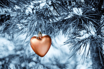 Toned picture of Xmas toy  like heart hangs on pine branch
