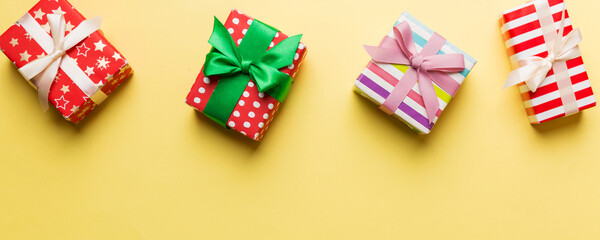 Fototapeta premium Holiday flat lay with gift boxes wrapped in colorful paper and tied decorated with confetti on colored background. Christmas, Birthday, Valentine and sale concept, top view