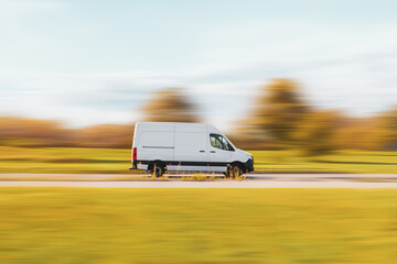 White Cargo Van. Cargo delivery bus is driving on an asphalt street with a blurred background