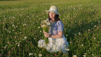 Woman Gathers A Large Bouquet Of Daisies On Field. Beauty Woman Enjoying Nature Outdoor. Enchanting Young Woman With Wildflowers Bouquet. Gimbal shot.