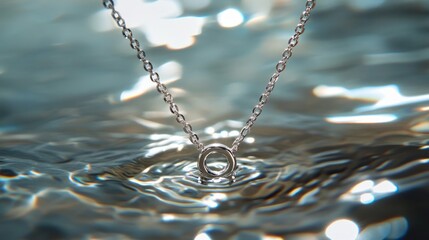A delicate silver necklace floating just beneath the surface of water, with sunlight casting shimmering patterns on the metal