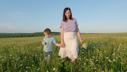 Mother And Son Walk Joining Hands In Rural Field Grass. Mother Hand With Her Little Son. Mom Holding Hands Walking. Gimbal Stabilize.