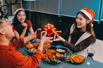 Group of young Asian man and women as friends having fun at a New Year's celebration, holding gift...