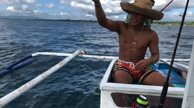 young man is fishing with a handline from a boat in deep sea waters.
