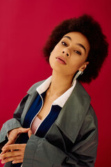 The young woman gazes thoughtfully, her expressive features captured against a bold pink setting.
