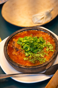 Fragrant Georgian dish ostri, stewed over low heat with tender beef, herbs and spices, is served in a traditional ketsi clay pot, demonstrating the rich taste of Georgian cuisine. Vertical photo