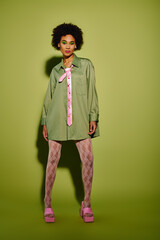 A young woman showcases her emotional style in a stylish green outfit, captivating attention.