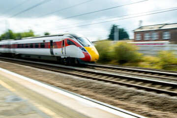 A Passing High Speed Passenger Train Flying Past A Train Station Platform