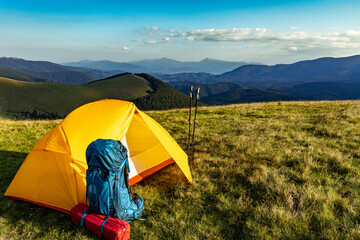 Hiking in the summer with a yellow tent in the mountains.