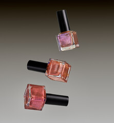 Different colored nail varnish bottles on a grey gradient background.