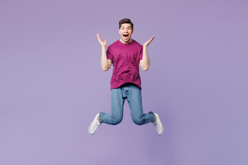 Full body young shocked surprised happy man he wear violet t-shirt casual clothes jump high look camera spread hands isolated on plain pastel light purple background studio portrait Lifestyle concept