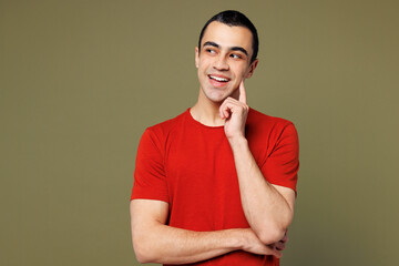 Young happy middle eastern man wear red t-shirt casual clothes put hand prop up on chin, lost in...
