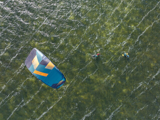 People swim on the sea on a kiteboard or kitesurfing. Kitesurfing lessons on the bay. Summer sport...