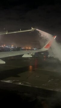 A technician treats an airplane wing with deicer before a flight.