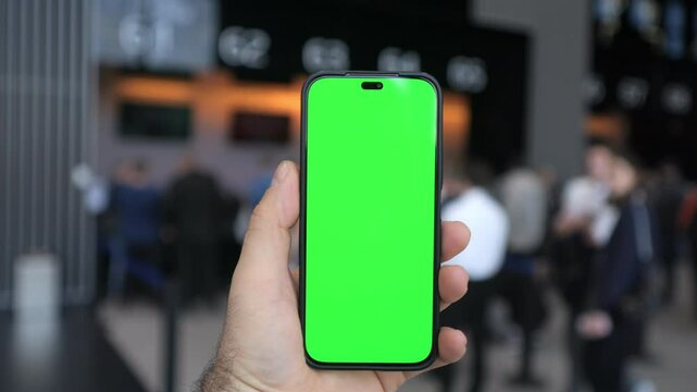 Handholding a smartphone equipped with a green screen suitable for various media applications