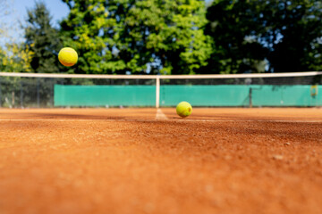 close-up of professional tennis a court with red clay surface with drawn markings of zones with tennis balls lying on it bounce off the field